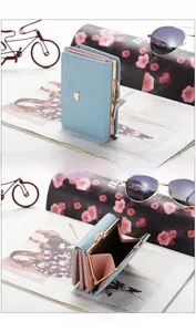 Detail view of the light blue short wallet with pink interior and heart hardware