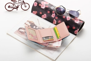 Detail of light pink tri-fold wallet showing multiple card slots and cash pocket