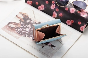 Detail of light blue tri-fold wallet with metal clasp coin pocket and pink lining details