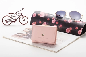 Close-up of pink tri-fold wallet with gold heart detail on a fashion magazine