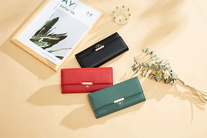 Close-up of three long leather wallets in black, red, and green with golden metal buckles
