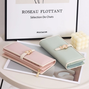 Detail of long PU leather wallets with gold bow buckles in pink and mint green colors