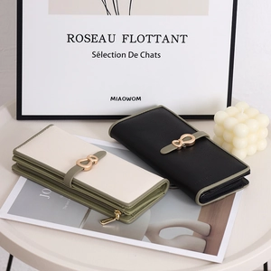 Detail of long wallets in black and off-white with gold buckle on a stylish table