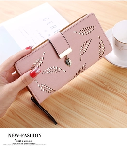 Detail of light pink long wallet featuring hollow leaf patterns and gold leaf pendant