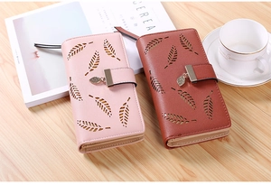 Detail of hollow leaf pattern and metal leaf pendant on long leather wallet with button