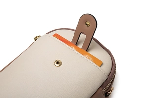 Close-up of dual-tone leather phone bag with magnetic buckle and golden zipper detail