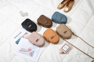 Detail view of mini crossbody phone bags in six matte colors on a quilted white surface