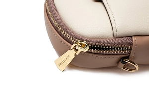 Close-up of cream and brown leather bag with high-quality gold zipper and precise stitching