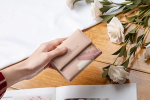Dettaglio portafoglio rosa in pelle PU con stampa floreale e logo in metallo oro
