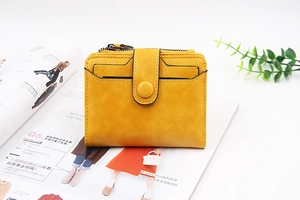 Close-up of ginger yellow PU leather wallet with snap closure and zipper pocket on a magazine
