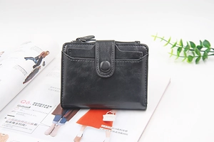 Detail view of black PU leather bifold wallet with card slots and zipper pocket on a magazine