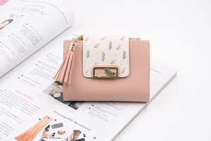 Close-up of pink PU leather wallet with floral print, tassel, and gold leaf buckle