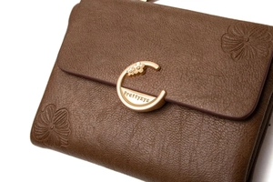 Macro shot of brown leather wallet with floral embossing and a gold metal clasp buckle