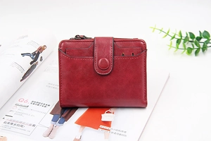 Detail of burgundy PU leather short wallet with zipper and snap closure on fashion magazine