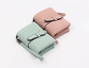 Close-up of mint green and dusty rose matte leather bifold wallets with wristlet straps