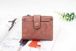 Close-up of a matte pink-brown short wallet with zipper pocket on a fashion magazine