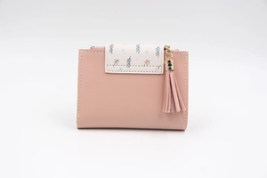 Detail of light pink foldable wallet with floral printed flap and gold tassel accent