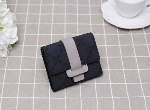 Vue détaillée du portefeuille noir matelassé avec fermoir gris sur une nappe à carreaux