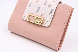 Détail du portefeuille rose en similicuir avec imprimés feuilles et boucle dorée