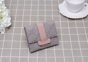 Détail du portefeuille matelassé gris avec fermoir rose contrasté et motif floral