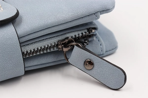 Detailed close-up of a light blue leather wallet featuring a premium metal zipper and puller