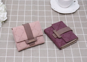 Gros plan de petits portefeuilles à trois volets avec gaufrage floral et fermeture à boucle