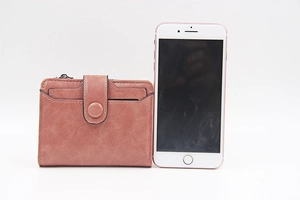 Detailed view of mauve PU leather wallet next to a phone showing compact portable size