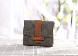 Gros plan d'un portefeuille à trois volets avec gaufrage floral et boucle en cuir