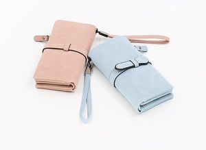 Detail of pink and blue matte long wallets featuring decorative straps and wristlets