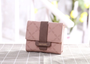 Détail d'un portefeuille rose pour femme avec motifs trèfle et fermoir contrasté