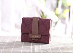 Détail du portefeuille bordeaux de luxe avec texture florale en relief et bouton pression