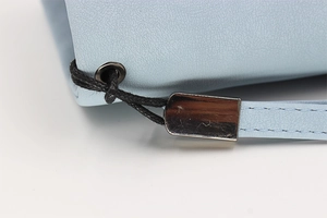 Macro detail of light blue lychee texture leather with silver metal hardware and stitching