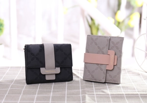 Gros plan sur le motif trèfle gaufré des portefeuilles en cuir avec boucle en métal