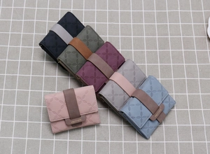 Détail des motifs trèfles embossés sur le portefeuille luxe en cuir mat brossé