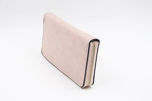 Vue latérale montrant la fermeture dorée et la texture mate du long portefeuille rose