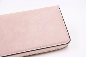 Détail du portefeuille long en cuir rose avec coutures fines et fermeture dorée