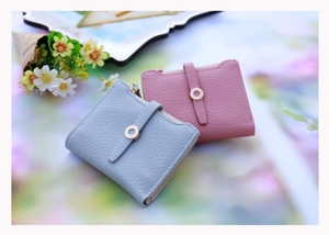 Detail of short women's wallets in pastel pink and blue with elegant pebble leather texture