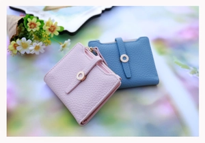 Detailed view of pink and blue bifold wallets with textured leather and gold hardware