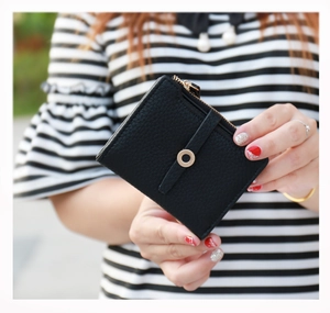 Close-up of black litchi grain leather wallet featuring a decorative gold metal ring