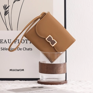 Close-up of caramel leather wallet with golden B buckle and convenient wrist strap