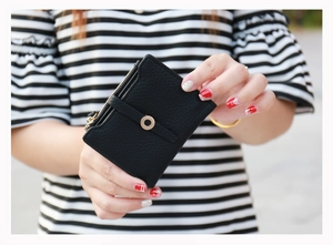 Close-up of black lychee grain leather short wallet with golden ring buckle and zipper