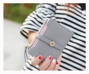 Close-up of compact grey lychee texture wallet with pink lining and gold clasp closure
