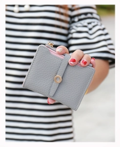 Close-up of women's short wallet with grey lychee grain leather and gold buckle detailing