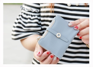 Close-up of light blue pebble leather wallet with zipper pocket and gold metal ornament