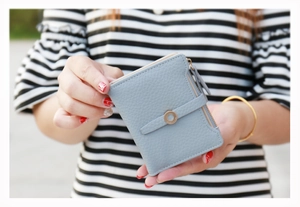 Detail of light blue lychee pattern leather wallet with zip and decorative metal buckle