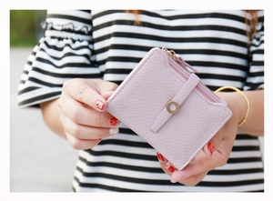 Close-up of pink litchi grain leather short wallet with gold zipper and round buckle