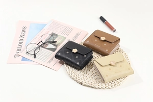 Three short printed wallets in black brown and beige leather with gold flower buckles