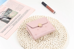 Close-up of pink leather wallet with floral print and gold flower clasp on a mat