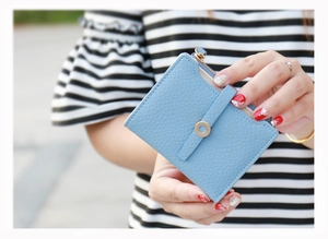Close-up of light blue lychee pattern leather wallet with gold zipper and clasp held by hand