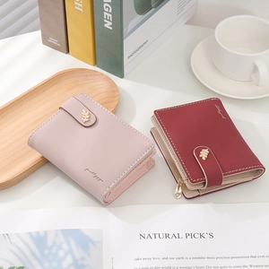 Close-up of minimalist women's short wallets with gold leaf buckles and heart zipper pulls